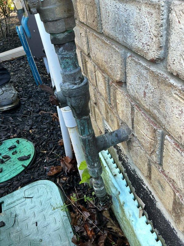 Removed and disconnected the existing backflow preventer assembly from the exterior irrigation system. The corroded metal piping and associated valve components were detached from the outdoor installation point along the building exterior, and the interior connection points were properly capped and secured to prevent water flow to the now-disconnected irrigation line.