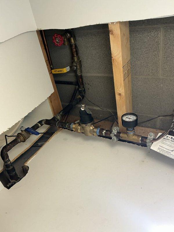 Removed and disconnected the existing backflow preventer assembly from the exterior irrigation system. The corroded metal piping and associated valve components were detached from the outdoor installation point along the building exterior, and the interior connection points were properly capped and secured to prevent water flow to the now-disconnected irrigation line.