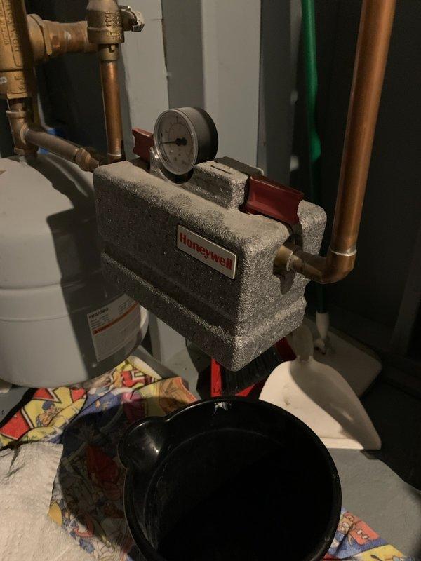 Responded to service call for water dripping from boiler pressure gauge. Upon inspection, identified leak at pressure relief valve connection point that worsened when outdoor water spigot was in use, indicating pressure fluctuation issue. Placed collection bucket beneath leak point to prevent water damage and assessed system for proper pressure regulation and expansion tank function.