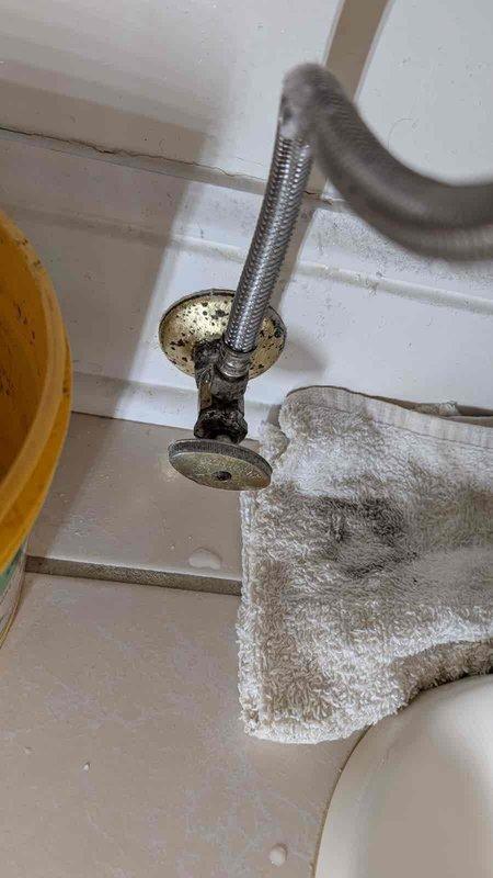 Responded to call for toilet leaking at floor connection during flushing after extended period of non-use. Upon inspection, identified corroded and deteriorated shut-off valve assembly with significant mineral buildup and water damage. Replaced faulty valve hardware and water supply line, ensuring proper seal at floor flange connection. Tested flush mechanism multiple times to verify leak was resolved and all connections remained watertight under operating pressure.