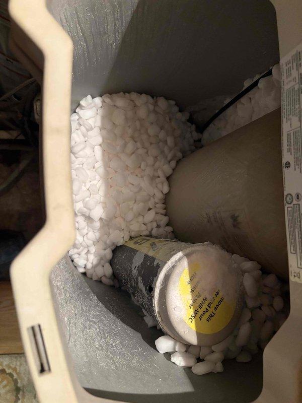 Responded to leaking valve located between water heater and water softener system. Diagnosed source of leak at valve connection point. Documented existing plumbing configuration including water filtration unit, PVC piping with marked flow directions, and flexible braided supply lines. Provided diagnostic assessment of valve failure and replacement recommendations to customer.