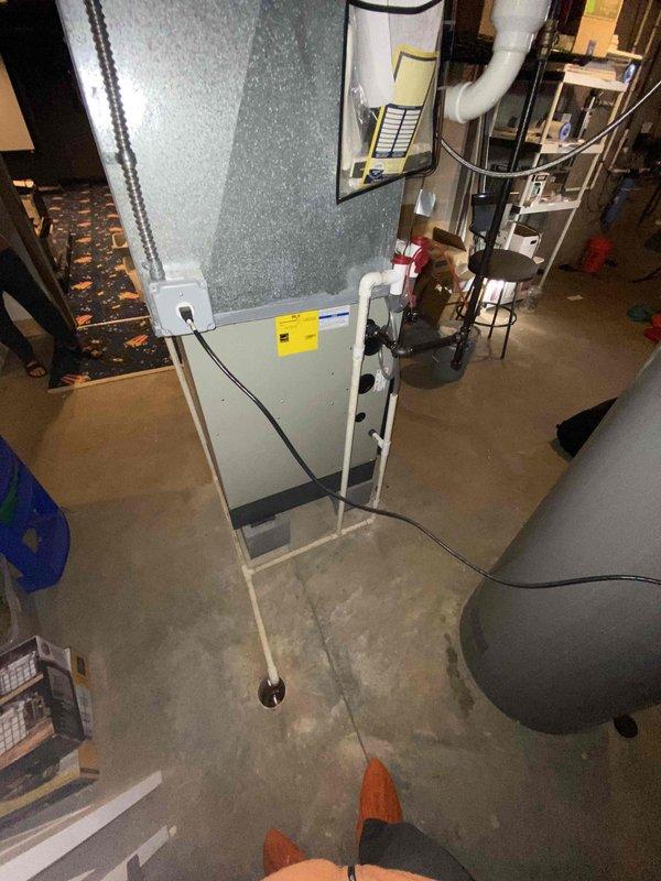 Completed HVAC estimate for air conditioning system replacement in basement mechanical room. Evaluated existing gray air handler unit with associated ductwork, electrical connections, and condensate pump system. Assessed current installation including water heater proximity and available space for equipment replacement. Documented existing system configuration with white PVC piping connections and electrical panel setup for accurate replacement specifications. Provided comprehensive quote for AC unit replacement as requested.