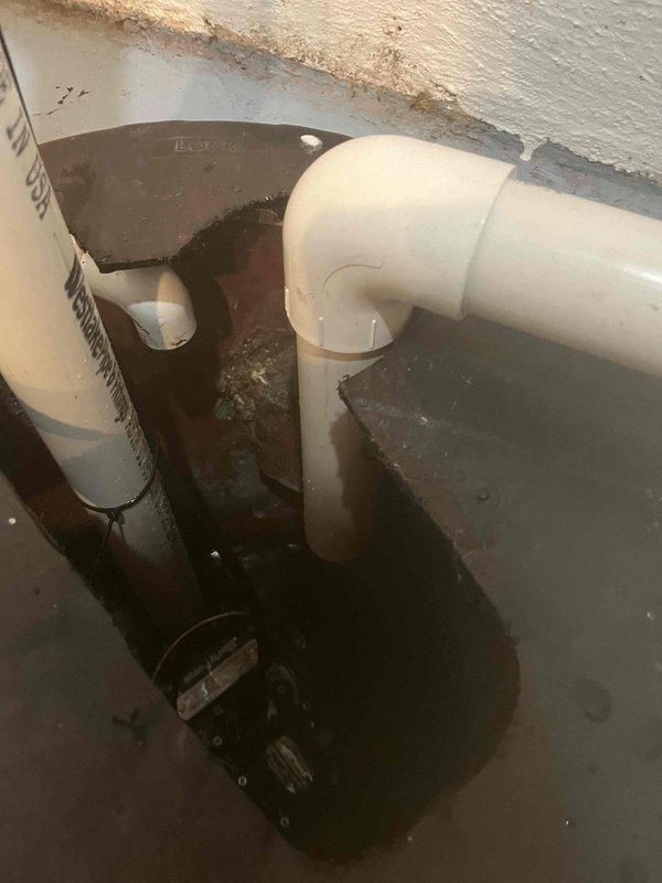 # Tankless Water Heater No Hot Water - Navien Unit

Responded to service call for 5-6 year old Navien tankless water heater not producing hot water. Upon inspection, discovered significant moisture accumulation and standing water in utility area surrounding condensate drainage system. Vertical PVC condensate drain line showed evidence of blockage with dark corrosion and residue buildup on drainage components. 

Identified compromised condensate neutralizer cartridge with heavy mineral deposits and deterioration. Standing water at floor level indicated drainage system failure preventing proper condensate removal. Cleared blockage from condensate drain line, replaced corroded neutralizer cartridge, and verified proper drainage flow. Tested unit operation and confirmed restoration of hot water delivery with proper condensate evacuation. Recommended monitoring for any recurrence of drainage issues and scheduled follow-up maintenance to prevent future condensate system failures.
