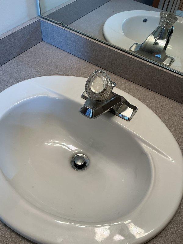 Completed plumbing membership maintenance visit addressing multiple fixtures throughout the property. Inspected upstairs bathroom sink with chrome single-handle faucet and identified worn washer requiring replacement to prevent future leaks. Examined upstairs toilet and diagnosed slow bowl fill issue by removing tank lid and inspecting internal components, noting low water level, mineral deposits at tank bottom, and fill valve assembly with red adjustment cap that may require calibration or component replacement. Evaluated downstairs toilet for proper operation. Conducted thorough inspection of hot water tank per previous service notes indicating potential replacement need, assessing unit condition, age-related wear, and operational efficiency. Documented all findings with photographs for maintenance records.