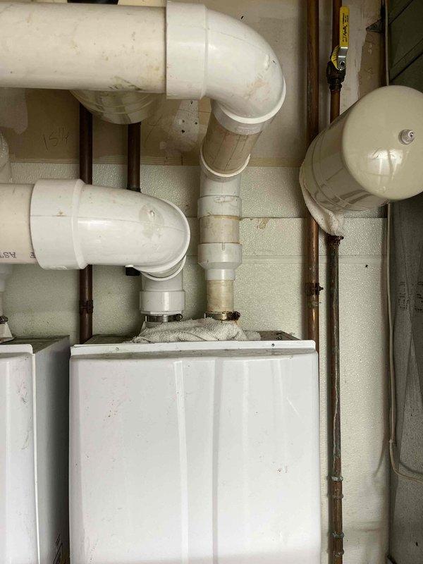 Responded to customer complaint of fluctuating water pressure in a fifteen-year-old residential property. Upon arrival, conducted comprehensive assessment of the plumbing system to identify the source of pressure inconsistencies.

Performed visual inspection of accessible plumbing fixtures and supply lines throughout the property. Examined chrome-plated fixture assembly at sink location, identifying significant mineral deposits and corrosion on brass connector nut and compression fittings. The buildup of scale and sediment on these components was contributing to restricted water flow and pressure variations.

Inspected main water supply system in utility area, documenting condition of PVC drainage and supply piping configuration. Evaluated the complex arrangement of pipes including multiple elbow joints and vertical/horizontal sections for potential flow restrictions or blockages. Assessed white metal utility cabinet housing plumbing connections for any signs of leaks or system degrada
