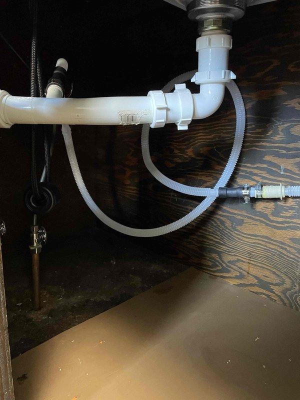 Extended dishwasher drain line under kitchen sink by installing additional PVC piping and flexible corrugated hose connections to properly route drainage. Modified existing P-trap assembly with new fittings and connectors to accommodate the extended drain configuration, ensuring proper drainage flow and code-compliant installation.