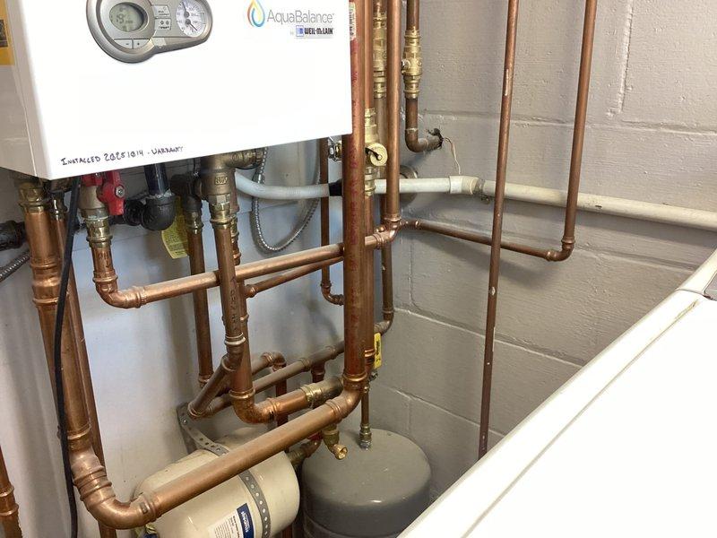Performed system evaluation and documented existing water heater and plumbing configuration. Customer was previously advised that boiler system requires acid neutralizer installation to protect equipment from condensate corrosion and extend system lifespan. Photographed current utility room setup showing water heater, copper piping network, valves, and existing water treatment components for service records.