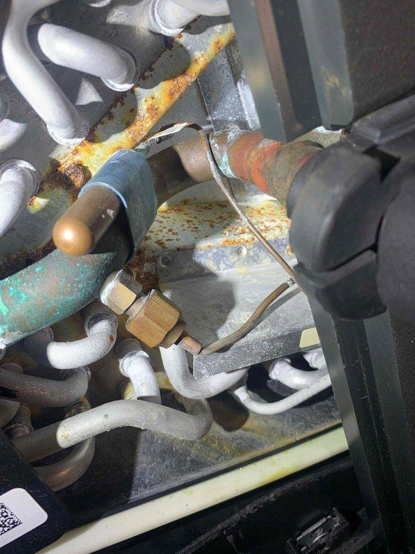 Completed routine AC tune-up on 6-year-old cooling system. Performed standard maintenance procedures including electrical testing with multimeter, which showed normal inrush current readings. Observed significant rust and corrosion on mounting brackets and refrigerant line connections during inspection. System currently operating within normal parameters despite visible oxidation on hardware components.