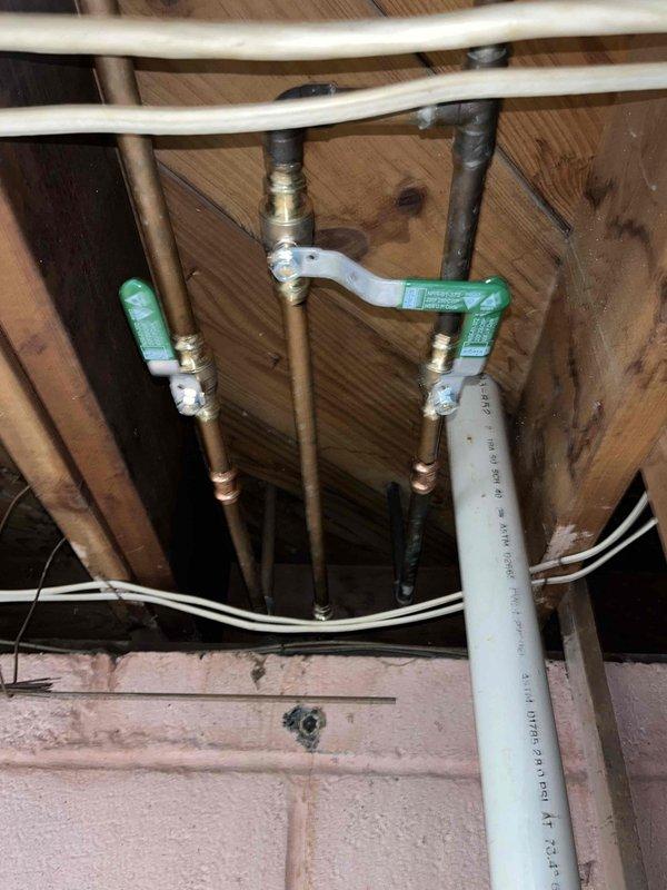 Responded to emergency call for outdoor hose bib leaking both inside and outside the residence upon activation. Inspected exterior spigot with green cross-handle valve and traced supply lines through crawl space to identify leak source at connection points between copper piping and valve assembly. Tightened brass fittings and dielectric union connections where copper pipes interface with PEX supply lines to eliminate water spray condition and restore proper function to outdoor water fixture.