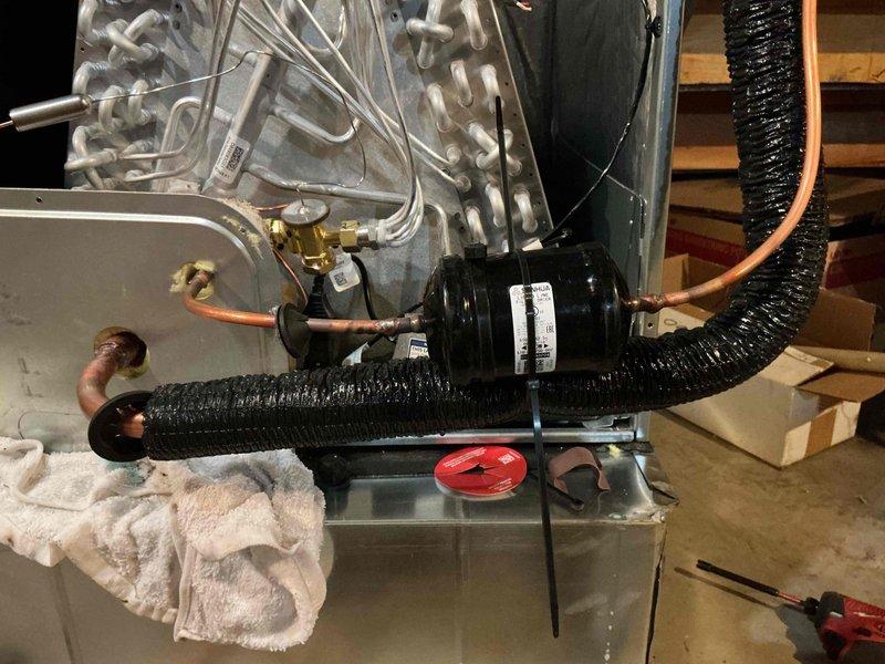 Completed full HVAC system installation including outdoor condensing unit and indoor air handler with proper leveling and refrigerant line connections. Installed emergency drain pan with float switch safety device beneath air handler unit, verified proper drainage, and ensured all copper refrigerant lines were securely connected with appropriate insulation to prevent condensation and energy loss.
