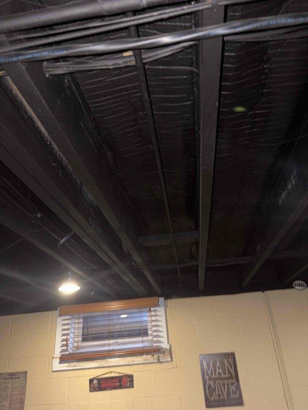 Conducted site assessment of existing hot water holding tank connected to oil boiler system in basement utility area. Evaluated current tank configuration and plumbing infrastructure, including overhead piping and supply lines visible in exposed ceiling joists. Documented existing conditions through photographic documentation of mechanical room layout, ductwork, insulation, and pipe routing. Assessed exterior back spigot plumbing to determine requirements for removing softened water supply line. Provided technical specifications and recommendations for upgraded tank installation and exterior spigot reconfiguration work to be completed during scheduled return visit to minimize water service interruption.