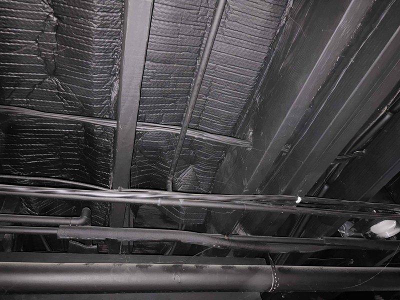 Conducted site assessment of existing hot water holding tank connected to oil boiler system in basement utility area. Evaluated current tank configuration and plumbing infrastructure, including overhead piping and supply lines visible in exposed ceiling joists. Documented existing conditions through photographic documentation of mechanical room layout, ductwork, insulation, and pipe routing. Assessed exterior back spigot plumbing to determine requirements for removing softened water supply line. Provided technical specifications and recommendations for upgraded tank installation and exterior spigot reconfiguration work to be completed during scheduled return visit to minimize water service interruption.