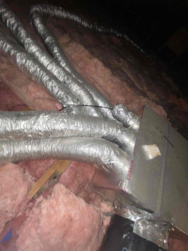 Conducted comprehensive HVAC system assessment for replacement estimate at property with existing boiler heating system and non-operational air conditioning unit that failed the previous year. Inspected attic-mounted ductwork system consisting of flexible aluminum ducts with multiple branches converging at central junction box, evaluated insulation conditions, and documented existing HVAC equipment configuration including dark-colored attic unit positioned between joists on fiberglass insulation for replacement recommendations.