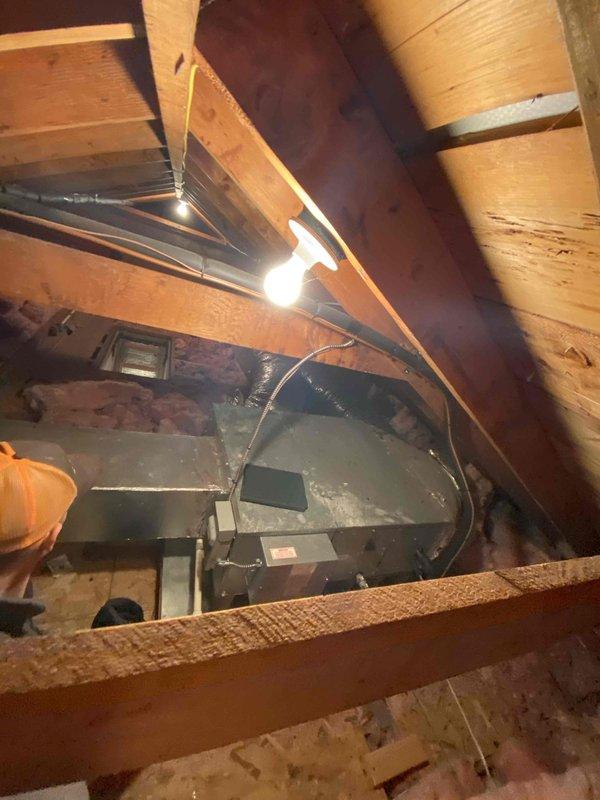 Conducted comprehensive HVAC system assessment for replacement estimate at property with existing boiler heating system and non-operational air conditioning unit that failed the previous year. Inspected attic-mounted ductwork system consisting of flexible aluminum ducts with multiple branches converging at central junction box, evaluated insulation conditions, and documented existing HVAC equipment configuration including dark-colored attic unit positioned between joists on fiberglass insulation for replacement recommendations.