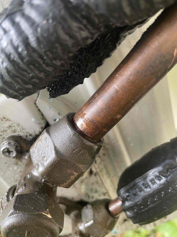 Responded to service call for mini split system displaying error code indicating refrigerant leak, consistent with previous issue from last spring. Upon inspection, identified compromised copper refrigerant line connections at exterior unit showing significant corrosion and weathering on compression fittings. Documented condition of copper piping and brass union connections displaying oxidation and patina from environmental exposure. System requires refrigerant leak repair at corroded connection points and complete refrigerant recharge to restore proper operation.