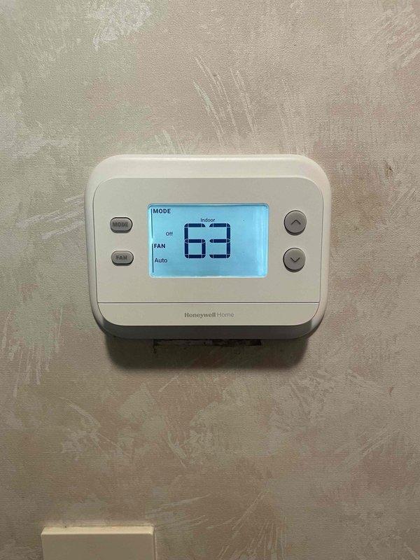 Returned to property to install previously sold motor and thermostat replacement. Removed existing Honeywell Home thermostat from wall and disconnected wiring from terminal block, documenting wire connections including R, C, W, Y, and G terminals. Installed new thermostat unit, reconnected all wiring to proper terminals per manufacturer specifications, and verified system powered on correctly with display showing indoor temperature reading. Tested thermostat operation in both system and fan modes to confirm proper communication with HVAC equipment.