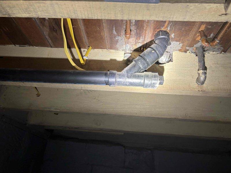 Completed return visit for clawfoot tub faucet installation with new toe tap drain in black finish and body spray fixtures. Materials were previously ordered and received approximately two weeks after initial consultation. Assessed existing plumbing infrastructure including exposed drain lines, copper water supply lines, and shut-off valve locations in basement access area. Verified proper drain and supply line routing through floor joists to accommodate new fixture placement. Inspected installation area including deteriorated flooring surfaces and existing plumbing connections requiring updates to support new clawfoot tub fixtures. Prepared site for installation of black finish toe tap drain assembly and body spray system with compatible supply lines and drainage configuration.