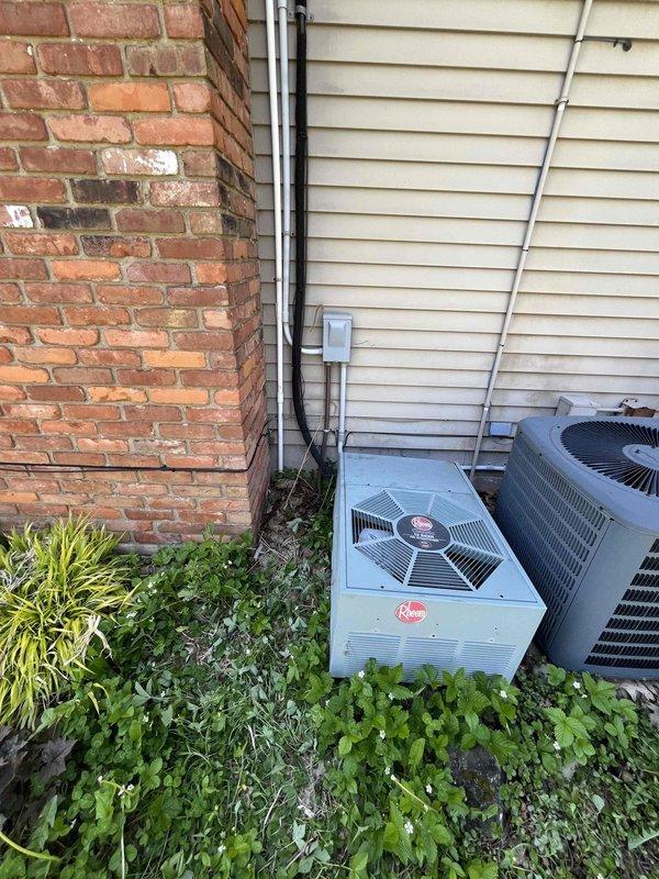 Conducted comprehensive site assessment for HVAC system replacement at residential property. Accessed attic-mounted equipment using ladder to evaluate existing system configuration and electrical connections. Inspected dual Rheem condensing units located on exterior side yard, documenting current equipment condition, electrical service panel with circuit breaker configuration, and associated conduit routing between units and main electrical panel. Photographed existing installation including weathered exterior equipment placement, electrical connections, and site conditions to support replacement system specifications and installation planning.