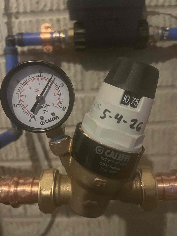 Responded to service call for leaking outdoor spigot and malfunctioning garbage disposal. Inspected and documented water pressure regulation system, including pressure reducing valve assembly with gauge reading and copper piping connections. Replaced non-functional garbage disposal unit and addressed outdoor spigot leak to restore proper operation of both plumbing fixtures.