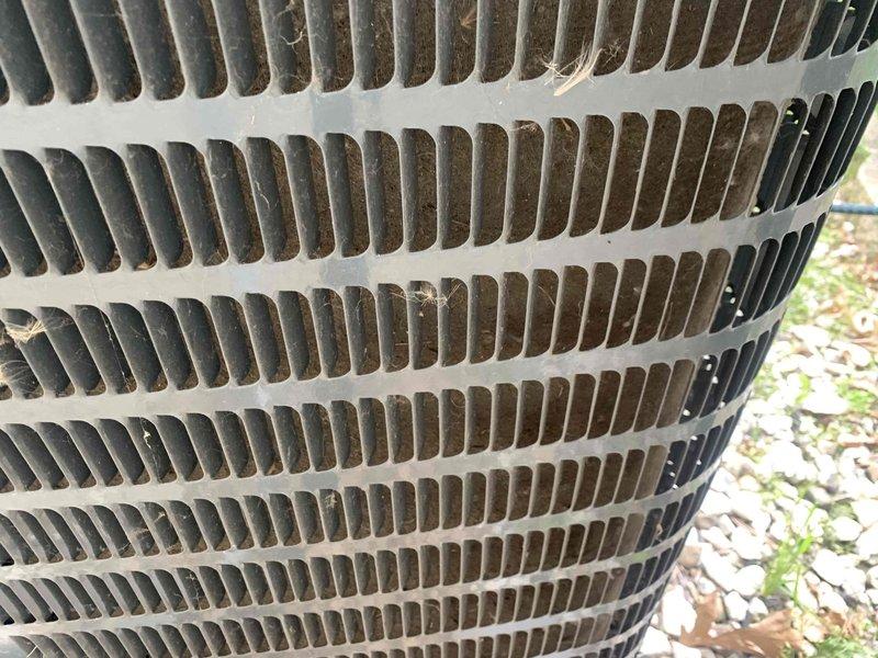 Completed routine AC maintenance and system diagnostics on outdoor condensing unit. Inspected condenser coil assembly, noting moderate dirt and debris accumulation between aluminum fins with some minor fin deformation present. Verified electrical operation with multimeter, recording 245.2 volts at unit, confirming proper power supply within acceptable range for equipment operation.