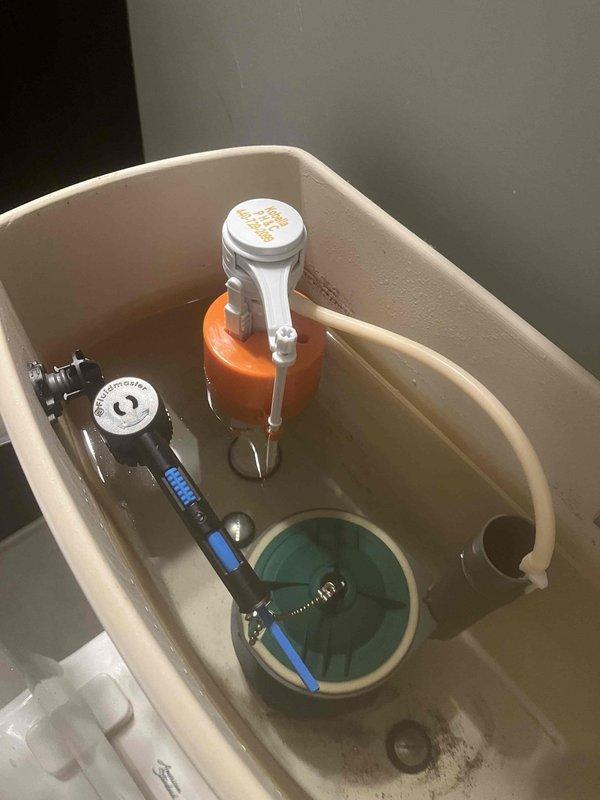 Replaced complete internal toilet tank components including flush valve assembly and fill valve mechanism. Removed deteriorated flapper, flush valve, and fill valve system. Installed new black flush valve assembly with overflow tube and flexible refill tube on left side of tank. Installed new fill valve with float mechanism and adjusted water level settings. Connected new flapper chain to flush lever and tested flush cycle for proper operation. Verified all connections for leaks and confirmed tank refills to appropriate water level after flushing.