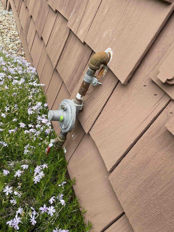 Responded to service call for non-operational garage heating unit previously installed by our company. Upon arrival, conducted diagnostic inspection of gas-fired heating system and associated gas supply infrastructure. Performed visual assessment and measurements of exterior gas meter assembly, including pressure regulator, supply piping, and shutoff valve to verify proper gas delivery to the structure. Documented existing conditions of gas meter installation, noting weathered brass fittings and copper piping connections showing age-appropriate patina and minor surface corrosion on exterior components. Verified gas meter functionality and measured clearances around regulatory equipment mounted on building exterior wall. System evaluation included photographic documentation of gas supply components for service records and future reference.