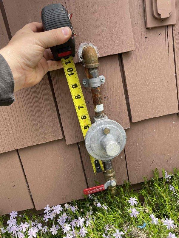 Responded to service call for non-operational garage heating unit previously installed by our company. Upon arrival, conducted diagnostic inspection of gas-fired heating system and associated gas supply infrastructure. Performed visual assessment and measurements of exterior gas meter assembly, including pressure regulator, supply piping, and shutoff valve to verify proper gas delivery to the structure. Documented existing conditions of gas meter installation, noting weathered brass fittings and copper piping connections showing age-appropriate patina and minor surface corrosion on exterior components. Verified gas meter functionality and measured clearances around regulatory equipment mounted on building exterior wall. System evaluation included photographic documentation of gas supply components for service records and future reference.
