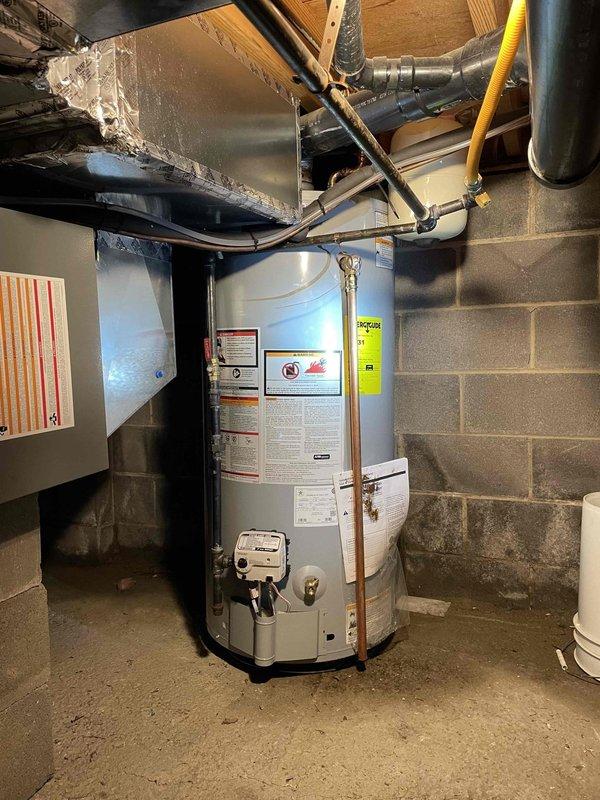 Returned to property to complete installation of 40-gallon standard capacity natural gas water heater. Unit was successfully installed in basement mechanical room with proper connections to existing copper supply lines and gas service line via flexible yellow gas connector. Verified proper combustion with blue flame pattern at gas burner assembly, confirming correct air-to-fuel mixture and safe operation. All plumbing connections were tested and secured, venting system properly configured with metallic ductwork, and unit positioned on concrete floor per manufacturer specifications. Water heater is fully operational with all safety labels and energy guide information visible for homeowner reference.