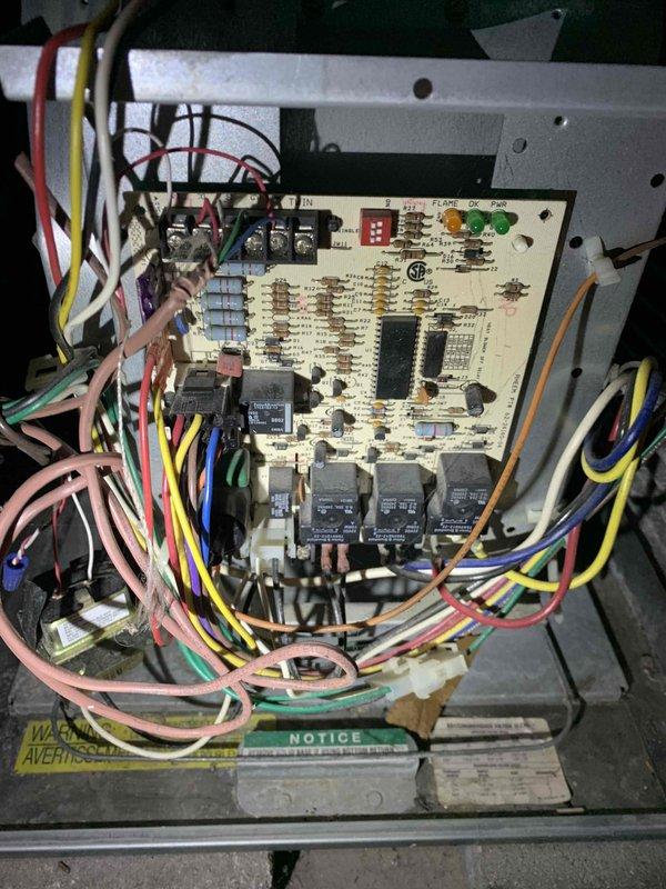 # HVAC Service Completed

Responded to no heat call on 20-year-old gas furnace. Upon arrival, performed system diagnostics to identify cause of heating failure. Inspected furnace control board and found multiple indicators of operational issues. 

Examined blower motor assembly and associated refrigerant lines connected to the cylindrical housing component. Noted dirt accumulation and minor discoloration on metal surfaces consistent with age of unit. Verified all electrical connections to control board, including multiple wire harnesses in various colors connecting to integrated circuits, relays, and LED indicators.

Assessed main control board mounted in metal chassis, which contained four black relay components and various electronic components. Tested circuit board functionality and checked all wire connections entering and exiting the assembly. Inspected capacitor, transformer, and associated safety controls.

Given the 20-year age of the furnace and observed condition of component