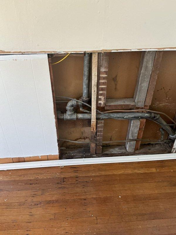 Responded to service call for cast iron pipe evaluation and plumbing modifications. Opened interior wall to access existing plumbing infrastructure and assess condition of aging cast iron piping system. Evaluated deteriorated cast iron pipe requiring future replacement due to age and condition. Capped off abandoned piping from previous kitchen installation to prevent potential leaks and ensure system integrity. Installed shut-off valves for bathroom sink to provide localized water control and facilitate future maintenance. Wall cavity remains open for additional plumbing work and final restoration.
