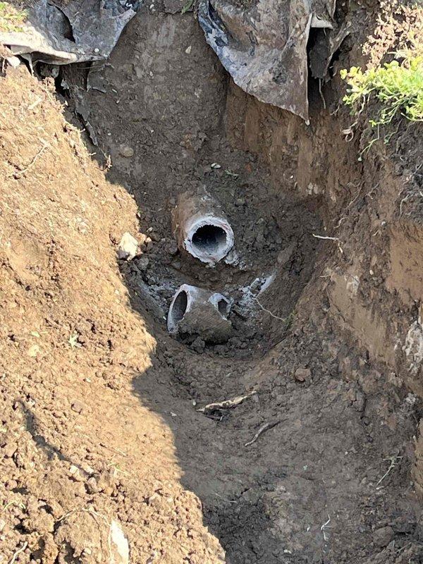 Excavated front yard sewer line to access and replace damaged underground plumbing. Trench was dug several feet deep, exposing deteriorated pipe sections that required removal. Installed new white PVC piping to restore proper sewer function, ensuring level installation and proper grade for drainage. Backfilled excavation upon completion of pipe replacement.