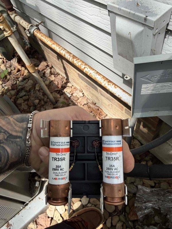 Completed cooling maintenance club visit on residential air handler system. Performed routine inspection of outdoor condensing unit located alongside building foundation. Inspected and photographed dual-element time-delay fuses (Ferraz Shawmut Tri-Onic TR35R, 35A 250V AC) removed from electrical disconnect for assessment. Noted significant corrosion present on exterior copper refrigerant lines requiring monitoring. Conducted standard preventative maintenance procedures on condenser unit including visual inspection of fan assembly and electrical components. System operational at time of departure.