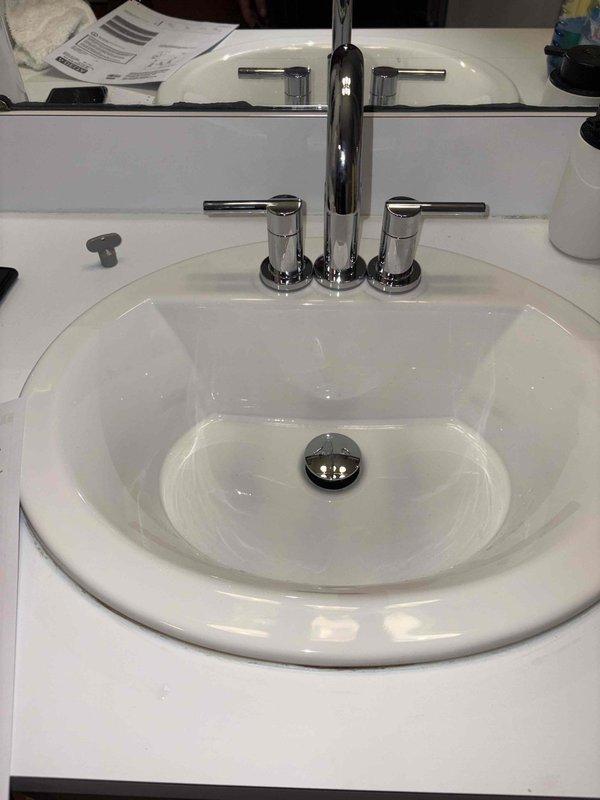 Successfully installed two customer-supplied chrome faucets in the kids' bathroom, including replacement of cartridges using specialized tools. The installation involved mounting the modern dual-handle faucets with center spouts onto white countertop surfaces, ensuring proper flow rate specifications (1.2 GPM/4.5 L/MIN) and secure connections. All fixtures were tested for proper operation and leak-free performance upon completion.