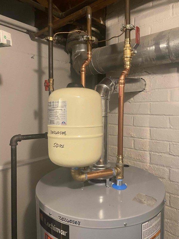 Responded to service call for 40-gallon gas water heater with leak at base of tank where bottom attaches to footer assembly. Upon inspection, confirmed active leak originating from lower tank seam, indicating internal tank failure. Documented existing installation including standard atmospheric venting, copper supply lines, expansion tank, pressure relief valve, and associated plumbing connections for replacement specifications.
