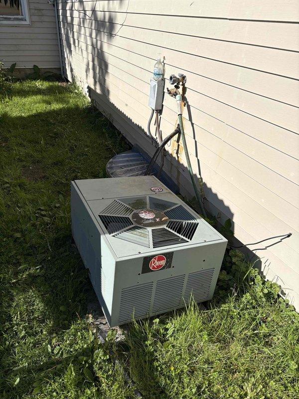 Conducted comprehensive HVAC system evaluation for complete replacement estimate on existing Rheem outdoor condensing unit. Assessed current equipment condition including weathered refrigerant line insulation, aged copper piping connections, and electrical disconnect configuration. Documented exterior condenser placement on concrete pad with overgrown vegetation clearance concerns. Evaluated interior plumbing infrastructure including water supply lines, shut-off valves, and copper piping showing corrosion and mineral buildup at connection points. Provided detailed photographic documentation of all system components to support replacement recommendations and equipment specifications.