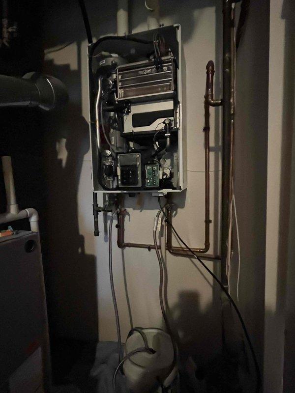 Responded to service call for 2-year-old Navien tankless water heater producing lukewarm water. Performed diagnostic inspection of unit, accessed internal components including heat exchanger, burner assembly, and control boards. Identified issue affecting proper heating operation, completed necessary repairs to restore full hot water temperature output, and verified system functionality before closing service panel.