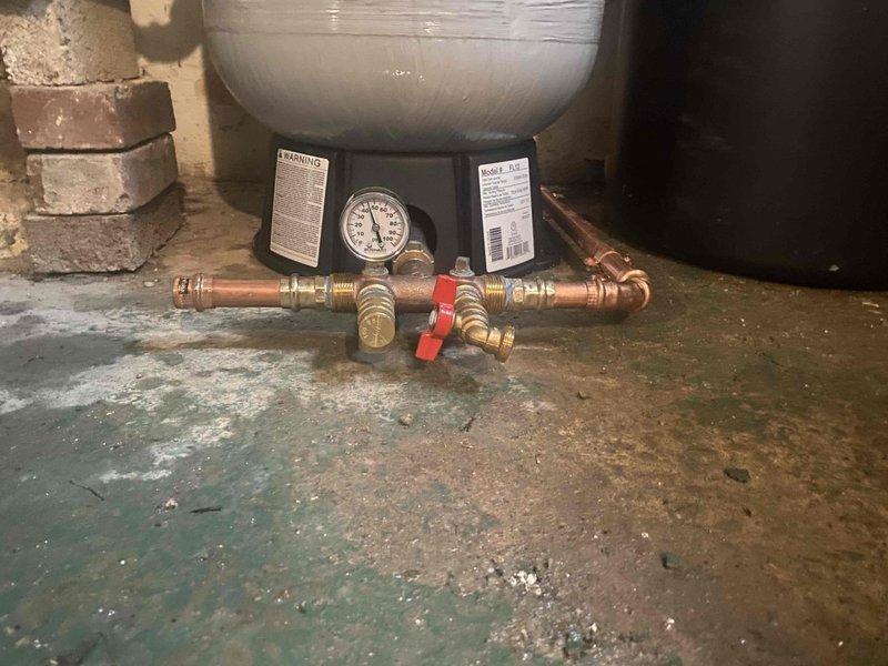 Responded to service call for malfunctioning water softener system. Upon arrival, inspected complete water treatment setup including Flex-Lite pressure tank, water softener with digital control head, expansion tank, and associated copper piping and brass valve assemblies. Diagnosed water softener control head failure preventing proper regeneration cycle. Assessed condition of all equipment and plumbing connections, noting significant floor staining indicating past water issues. Presented property representative with repair versus replacement options for approval, including cost analysis for new water softener installation versus control head replacement on existing unit.