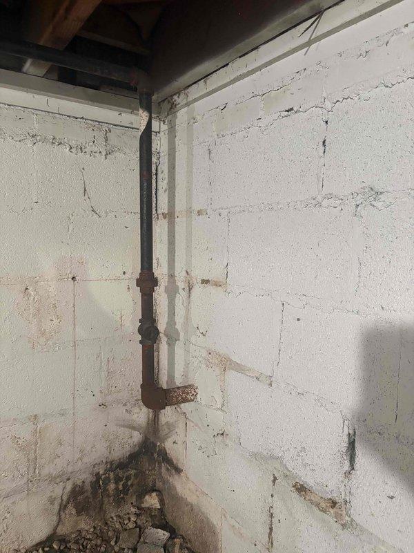 Responded to emergency call for reported gas odor detected both inside and outside the property near the meter area of a 1952-built residence. Upon arrival, conducted thorough visual inspection of gas system components including interior piping and exterior meter assembly. Documented extensive corrosion and deterioration on metal gas piping throughout the system, particularly noting severe rust accumulation on interior vertical gas line running from ceiling to floor level with significant oxidation at base connections and wall penetration points. Exterior inspection revealed gas meter installation with heavily corroded brown metal piping showing advanced rust deterioration on all exposed surfaces and fittings. Performed comprehensive gas leak detection testing using appropriate detection equipment to identify source of reported odor. Evaluated structural integrity of aging gas distribution system and assessed safety concerns related to corroded piping condition. Provided recommendation