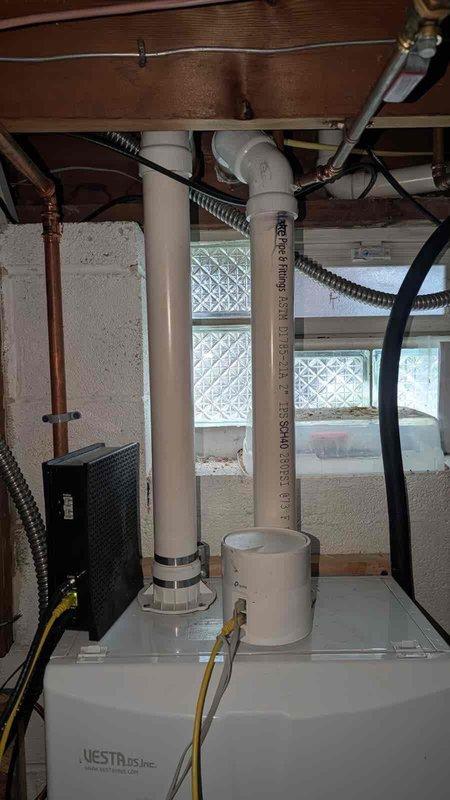 Installed fresh air intake system in basement utility area. Routed new PVC piping vertically through floor joists to upper level, connecting to existing copper plumbing lines in attic space using threaded compression fittings. Secured all piping and conduits to structural elements with appropriate straps and fasteners. Documented installation with photographs showing completed radon mitigation integration and upper-level pipe connections.