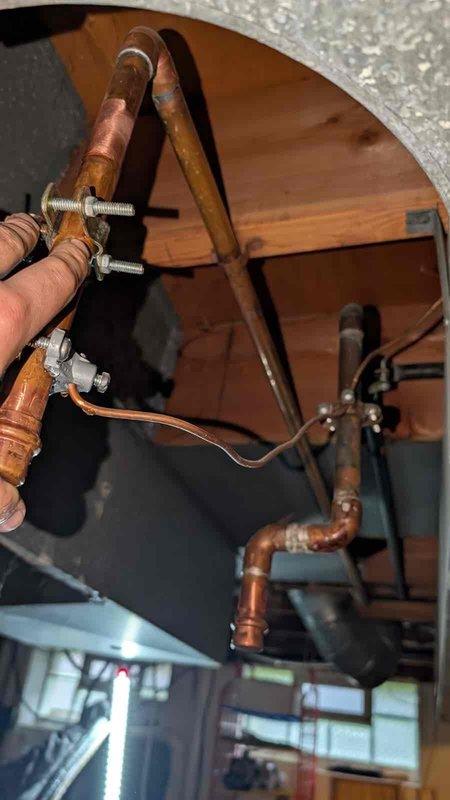 Installed fresh air intake system in basement utility area. Routed new PVC piping vertically through floor joists to upper level, connecting to existing copper plumbing lines in attic space using threaded compression fittings. Secured all piping and conduits to structural elements with appropriate straps and fasteners. Documented installation with photographs showing completed radon mitigation integration and upper-level pipe connections.