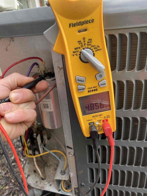 Completed routine cooling maintenance member visit on residential HVAC system. Performed comprehensive inspection of outdoor condensing unit, including examination of dual-run capacitor showing 25 MFD and 5 MFD ratings with proper terminal connections. Verified electrical connections and wire routing throughout unit, with all colored leads properly secured to capacitor terminals. Utilized Fieldpiece SC440 clamp meter to measure system amperage, recording reading of 485.6 during diagnostic testing. Inspected internal components within access panel, confirming all wiring connections remain tight and secure with no signs of deterioration. Unit operating within normal parameters with no immediate service needs identified.