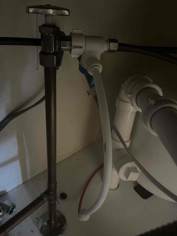 Completed water treatment system maintenance by servicing MRO filters and inspecting associated equipment. Installed new water treatment tank with control valve assembly and blue-handled bypass component, marked with installation date for future reference. Verified proper operation of under-sink plumbing connections, including supply lines, shut-off valves, and PVC drain system to ensure full system integration and functionality.