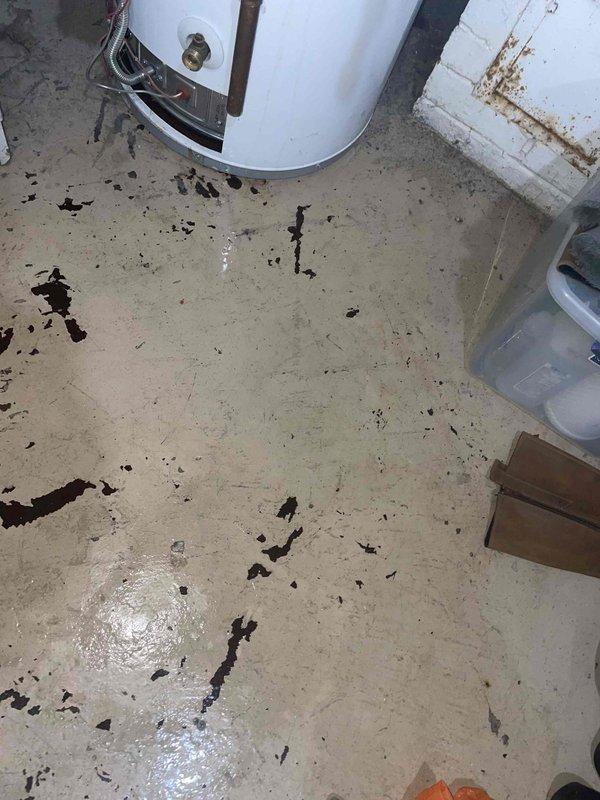Responded to service call for 40-gallon standard atmospheric gas water heater experiencing leaking from bottom of unit. Upon arrival, found significant water accumulation on utility room floor with standing water and debris present. Visual inspection revealed extensive rust and corrosion along bottom seam and base of water heater tank, indicating tank failure. Unit was approximately 4-5 years old, which is premature failure for typical residential gas water heater. Corrosion patterns and greenish oxidation consistent with galvanic corrosion or manufacturing defect causing accelerated deterioration of tank integrity. Documented conditions with photographs showing floor water damage and corroded tank bottom. Advised customer that tank failure requires complete water heater replacement as tank leaks cannot be repaired. Recommended immediate replacement to prevent further water damage to surrounding area and property.