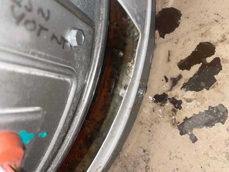 Responded to service call for 40-gallon standard atmospheric gas water heater experiencing leaking from bottom of unit. Upon arrival, found significant water accumulation on utility room floor with standing water and debris present. Visual inspection revealed extensive rust and corrosion along bottom seam and base of water heater tank, indicating tank failure. Unit was approximately 4-5 years old, which is premature failure for typical residential gas water heater. Corrosion patterns and greenish oxidation consistent with galvanic corrosion or manufacturing defect causing accelerated deterioration of tank integrity. Documented conditions with photographs showing floor water damage and corroded tank bottom. Advised customer that tank failure requires complete water heater replacement as tank leaks cannot be repaired. Recommended immediate replacement to prevent further water damage to surrounding area and property.