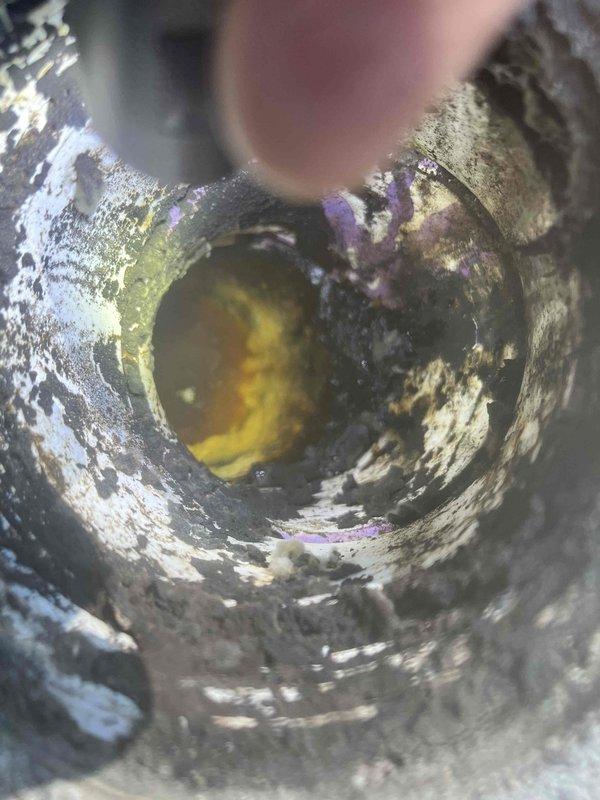 Responded to clogged drain under ice machine. Previous technician had snaked the line 15 feet, but blockage persisted. Upon inspection, found significant corrosion, mineral deposits, and buildup throughout the drain pipe interior with yellowish-brown sediment accumulation. Documented pipe condition showing extensive deterioration and heavy scaling on metal surfaces that may require future attention beyond standard drain cleaning.