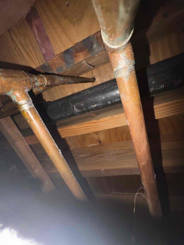 Responded to water leak service call and located pinhole leak in copper pipe within attic crawl space. Repaired compromised section of copper piping showing corrosion and oxidation, replaced deteriorated connection point with visible mineral deposits and rust accumulation, and verified system integrity upon completion.