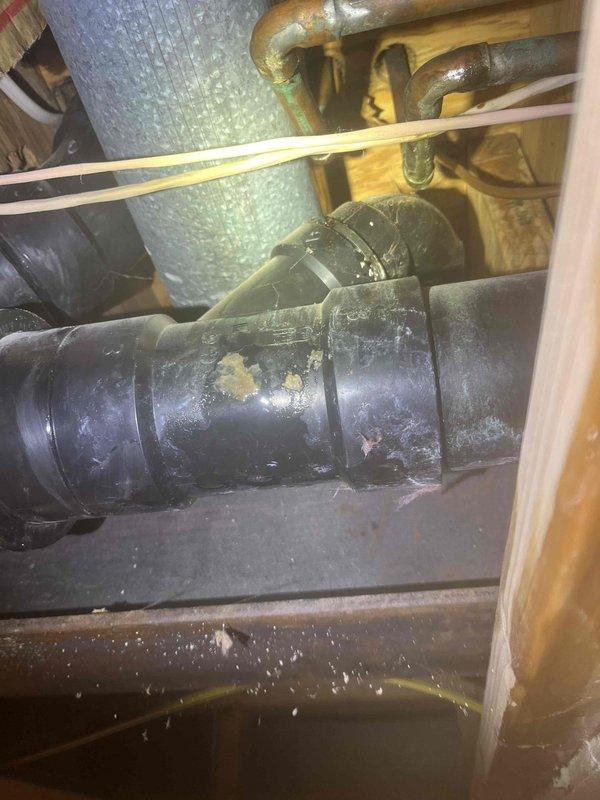 Responded to water leak complaint with visible water staining on basement drywall ceiling directly below kitchen refrigerator area. Inspected double kitchen sink with garbage disposal and found left basin completely blocked with standing water. Upon investigation of under-sink plumbing, identified failed garbage disposal unit and deteriorated sink fixture with corroded drain components and mineral buildup on piping. Horizontal drain line configuration showed signs of improper drainage and component failure. Documented existing conditions of compromised plumbing system including worn disposal unit, aged sink assembly, and affected ceiling area below for repair recommendations.