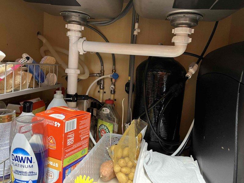 Completed plumbing membership inspection at residential property. Inspected exterior hose bib and connection on building exterior, verifying proper operation and checking for leaks or damage to the fixture and surrounding components. Examined under-sink plumbing system in kitchen, including dual basin drain configuration with P-trap assemblies and all connecting pipes, confirming proper drainage function and absence of leaks.