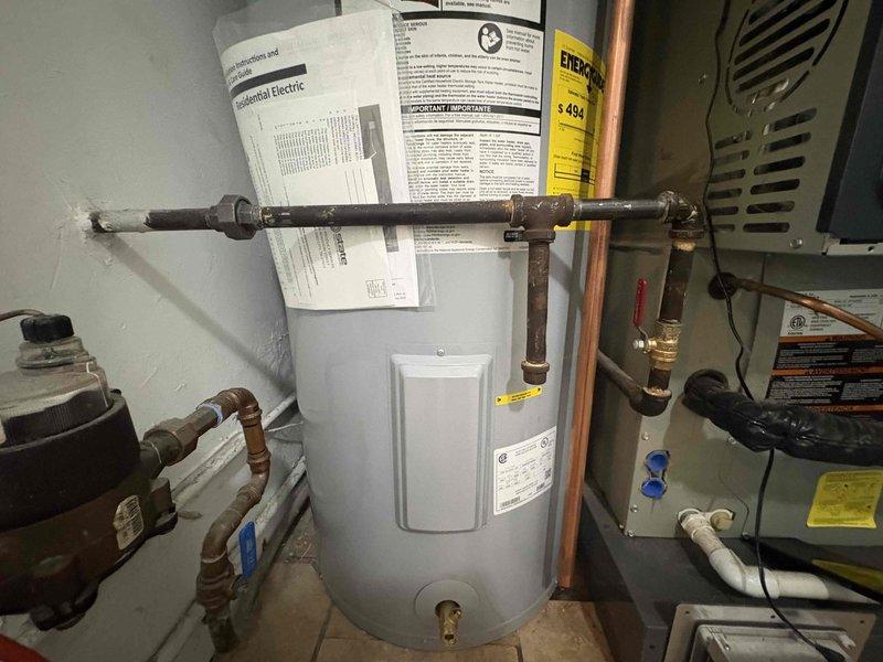 Completed return visit for previously sold 50-gallon electric water heater installation. Upon arrival, inspected the newly installed unit and verified proper operation of all components. The water heater was functioning correctly with all plumbing connections secure and free of leaks. Examined the copper supply piping connected to the top of the unit, including hot and cold water lines with appropriate shut-off valves. Confirmed proper electrical connections and grounding. Verified temperature and pressure relief valve installation and discharge piping compliance. All installation documentation and manufacturer instructions were posted on the wall behind the unit for homeowner reference. System tested and operational with no issues identified.