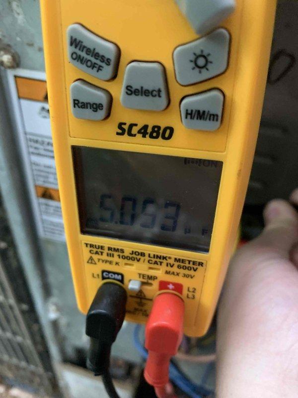 Responded to no cooling complaint with unit blowing warm air. Upon arrival, performed diagnostic assessment of outdoor condenser unit and measured electrical readings using digital multimeter, which indicated 6063 on display during testing. Inspected condenser unit exterior, noting accumulated debris and dirt on top panel and surrounding area, with vegetation growth encroaching on unit perimeter. Conducted systematic troubleshooting to identify root cause of warm air issue and verified thermostat display was functioning properly at time of service.